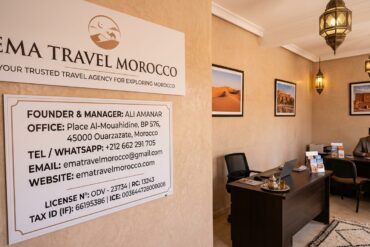 Interior of the Ema Travel Morocco office in Ouarzazate displaying contact details, founder Ali Amanar, and official agency licensing information.